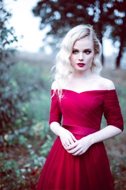 Moda güzel sarışın genç kadın bir masal ormandaki güzel Kırmızı elbiseli. sihirli bir atmosfer. Düzeltisiz tonlama atış