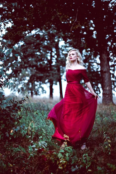 Moda linda jovem loira em belo vestido vermelho em uma floresta de conto de fadas. atmosfera mágica. Tonificação retocada tiro — Fotografia de Stock