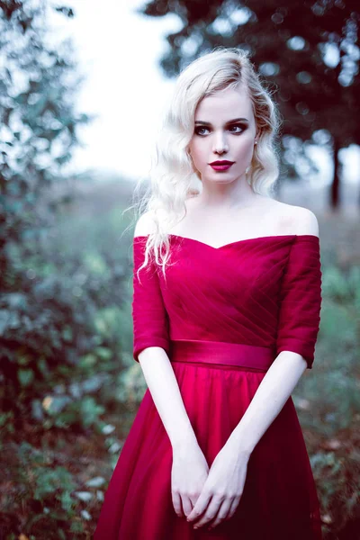 Mode hinreißende junge blonde Frau in schönen roten Kleid in einem Märchenwald. Magische Atmosphäre. retuschierte Tonung Schuss — Stockfoto
