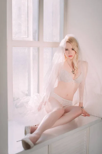 Mooie sexy dame in elegante witte lingerie dragen bruidssluier. Portret van fashion model meisje binnenshuis. Beauty blonde vrouw in lace lingerie. Vrouwelijk lichaam in ondergoed. Studio geretoucheerd schot — Stockfoto