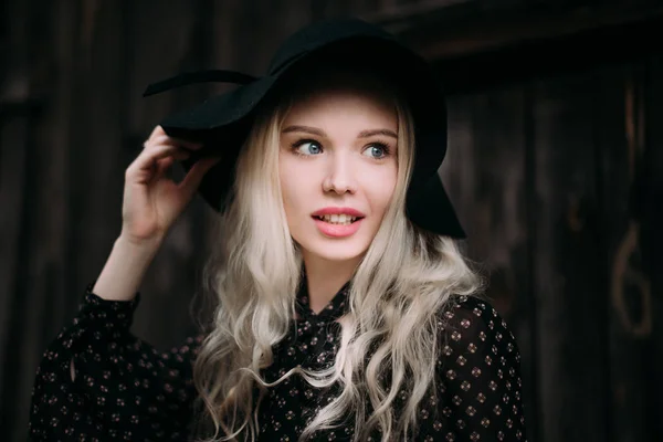 Hermosa chica atractiva y elegante con sombrero negro de pie posando en la ciudad. Maquillaje desnudo, mejor peinado diario y gran estilo de país glamour moda. Foto retocada — Foto de Stock