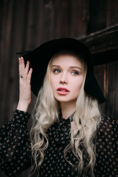 Hermosa chica atractiva y elegante con sombrero negro de pie posando en la ciudad. Maquillaje desnudo, mejor peinado diario y gran estilo de país glamour moda. Foto retocada — Foto de Stock