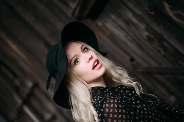 Krásná atraktivní a elegantní dívka, která nosí černý klobouk postavení pózuje v městě. Nahé líčení, denní účes a velké módní glamour venkovském stylu. Retušované fotografie — Stock fotografie