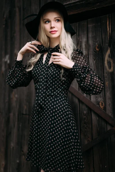 Όμορφη ελκυστική και μοντέρνα κοπέλα φορώντας μαύρο καπέλο στέκεται ποζάρουν στην πόλη. Nude μακιγιάζ, καλύτερο καθημερινό χτένισμα και μεγάλη Μόδα γοητεία εξοχικό στιλ. Retouched φωτογραφία — Φωτογραφία Αρχείου