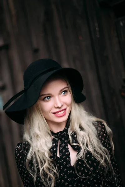 Piękny atrakcyjne i stylowe dziewczyna ubrana w czarny kapelusz stojący pozowanie w mieście. Nagie makijaż, Najlepsze fryzury dzienne i mody glamour wiejskim stylu. Retuszować zdjęcia — Zdjęcie stockowe