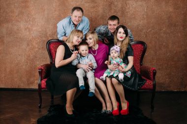 Üç nesil aile birlikte kanepede oturuyor. Klasik portre