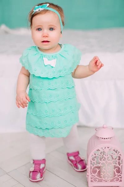 Adorable niña riéndose, sonriendo, arrastrándose y jugando en el estudio con vestido de menta — Foto de Stock