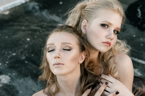 Glamour maquiagem duas mulheres com estilo de cabelo longo sentado no fundo da parede da rua no escuro. Retrato de cor da moda — Fotografia de Stock