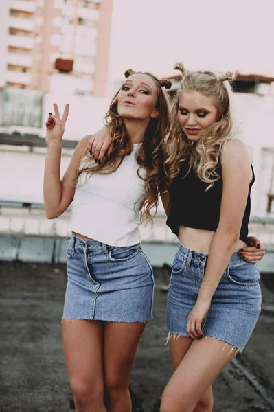 Style de vie et concept de personnes : Portrait de mode de deux filles élégantes meilleurs amis portant des jupes en jeans, à l'extérieur sur le toit. Bonne heure d'été pour s'amuser . — Photo