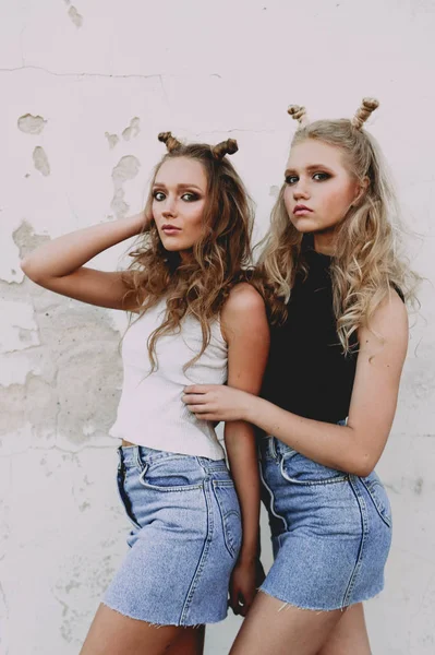 Lifestyle and people concept: Fashion portrait of two stylish girls best friends wearing jeans skirts, outdoors on the roof. Happy summer time for fun. — Stock Photo, Image