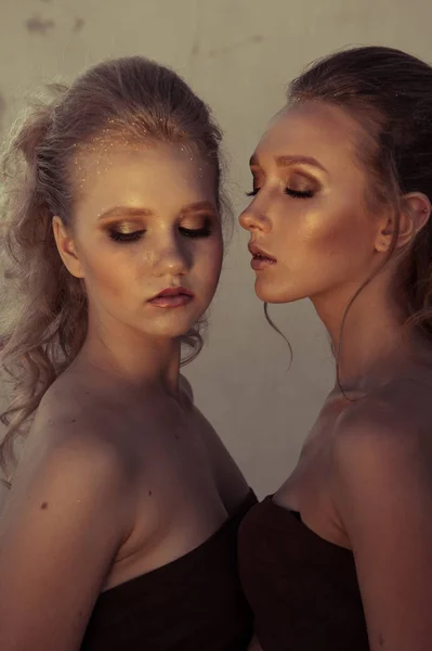 Glamour make-up twee vrouwen met lange haren stijl zittend op straat muur achtergrond in donker. Fashion kleur portret — Stockfoto