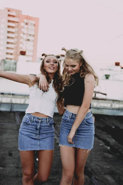 Yaşam tarzı ve insanlar kavramı: moda portre kot etek, açık havada çatıda giyen iki şık kızlar en iyi arkadaş. Eğlenmek için mutlu yaz saati. — Stok fotoğraf