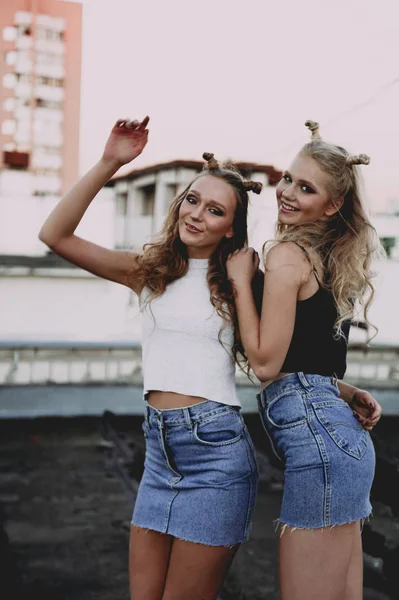 Style de vie et concept de personnes : Portrait de mode de deux filles élégantes meilleurs amis portant des jupes en jeans, à l'extérieur sur le toit. Bonne heure d'été pour s'amuser . — Photo