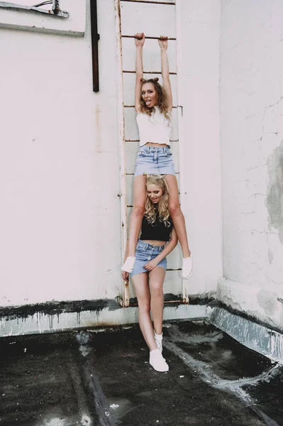 Estilo de vida y el concepto de la gente: Retrato de moda de dos chicas con estilo mejores amigos con faldas vaqueros, al aire libre en el techo. Feliz verano por diversión . —  Fotos de Stock