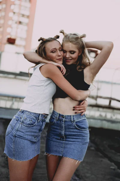 Lifestyle- und People-Konzept: Modeporträt zweier stilvoller Freundinnen in Jeansröcken, draußen auf dem Dach. fröhliche Sommerzeit zum Spaß. — Stockfoto