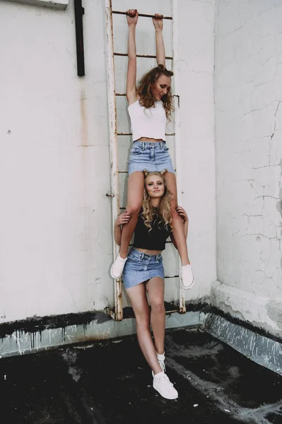 Style de vie et concept de personnes : Portrait de mode de deux filles élégantes meilleurs amis portant des jupes en jeans, à l'extérieur sur le toit. Bonne heure d'été pour s'amuser . — Photo