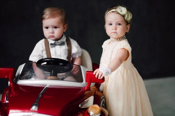 Två bebisar bröllop - pojke och flicka utklädd till bruden och brudgummen leker med leksaksbil — Stockfoto