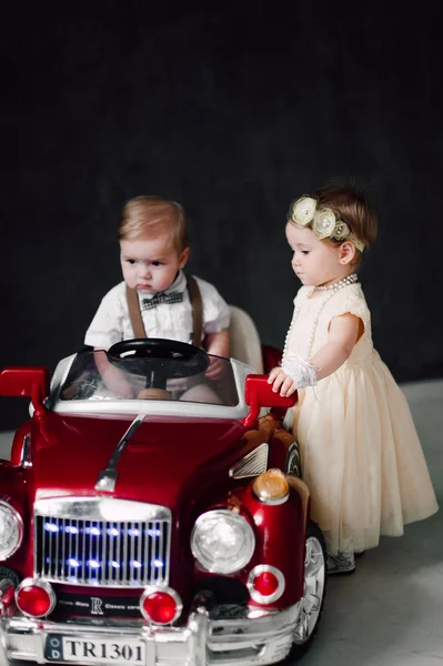Två bebisar bröllop - pojke och flicka utklädd till bruden och brudgummen leker med leksaksbil — Stockfoto