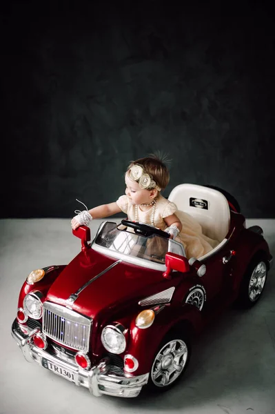 Casamento de dois bebês - menina vestida de noiva brincando com carro de brinquedo — Fotografia de Stock