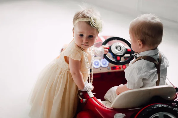 Två bebisar bröllop - pojke och flicka utklädd till bruden och brudgummen leker med leksaksbil — Stockfoto