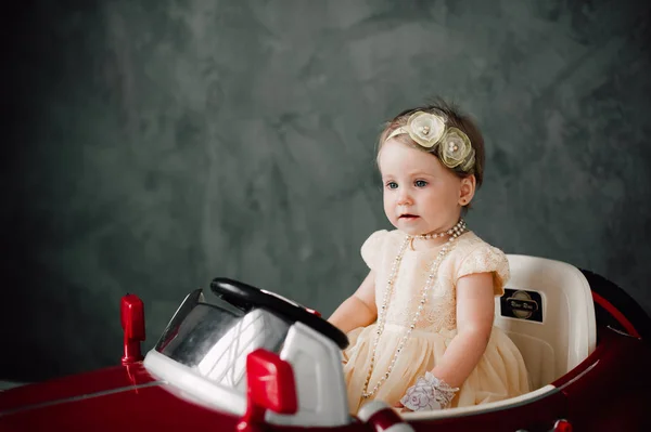 Свадьба двух малышей - девушка, одетая как невеста, играющая с игрушечным автомобилем — стоковое фото