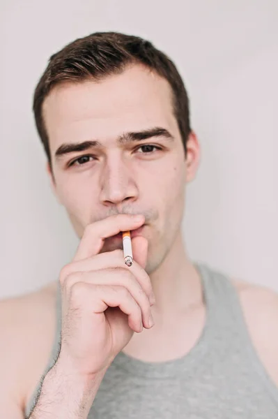 Крупным планом портрет красивого молодого человека, курящего сигару по Whi — стоковое фото