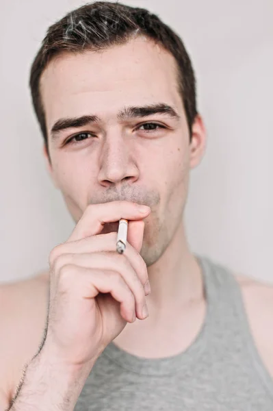 Gros plan portrait d'un beau jeune homme fumant un cigare sur whi — Photo