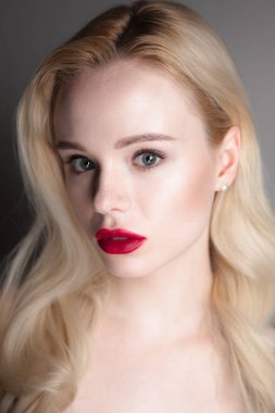 Güzellik modeli kız mükemmel makyaj ile kırmızı dudaklar ve mavi gözleri kameraya bakıyor. Sarışın çekici genç kadın portresi. Güzel kadın yüzü ile taze cilt temizleyin. Moda yakın atış.