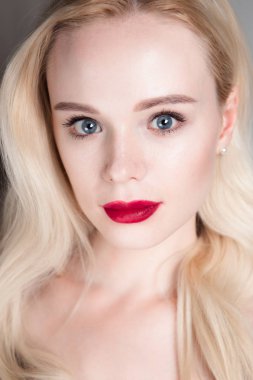 Güzellik modeli kız mükemmel makyaj ile kırmızı dudaklar ve mavi gözleri kameraya bakıyor. Sarışın çekici genç kadın portresi. Güzel kadın yüzü ile taze cilt temizleyin. Moda yakın atış.