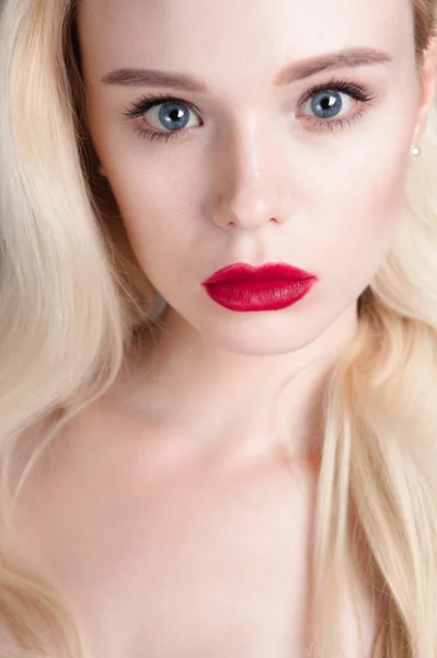 Skönhet modell flicka med perfekt make-up röda läppar och blå ögon tittar på kameran. Porträtt av attraktiv ung kvinna med blont hår. Vackra kvinnliga ansikte med tydliga fräsch hud. Mode närbild skott. — Stockfoto