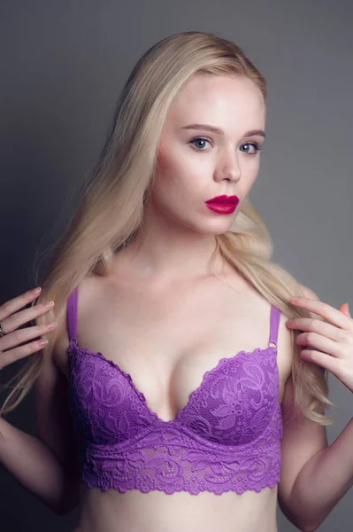 Schoonheid model meisje met perfecte make-up rode lippen en blauwe ogen kijken camera, magenta beha dragen. Portret van aantrekkelijke sexy jonge vrouw met blond haar. Mooie vrouwelijke gezicht met duidelijk vers sk — Stockfoto