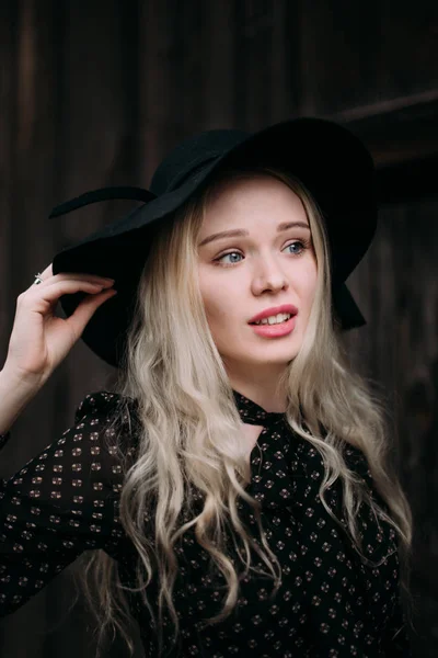 Beautiful attractive and stylish girl wearing black hat standing posing in city. Nude makeup, best daily hairstyle and great fashion glamour country style. — Stock Photo, Image