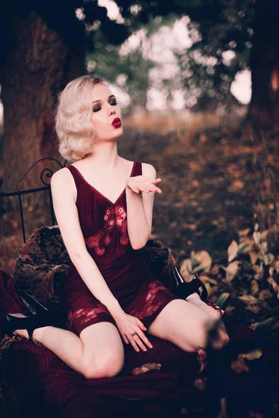 Mulher loira bonita e elegante com lábios vermelhos e ondas de cabelo vestindo vinho camisa vermelha posando na cama ao ar livre outono, estilo vintage retro e moda . — Fotografia de Stock