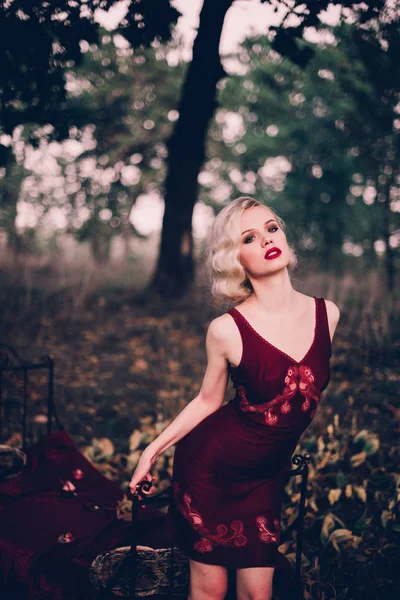 Mulher loira bonita e elegante com lábios vermelhos e ondas de cabelo vestindo vinho camisa vermelha posando na cama ao ar livre outono, estilo vintage retro e moda . — Fotografia de Stock