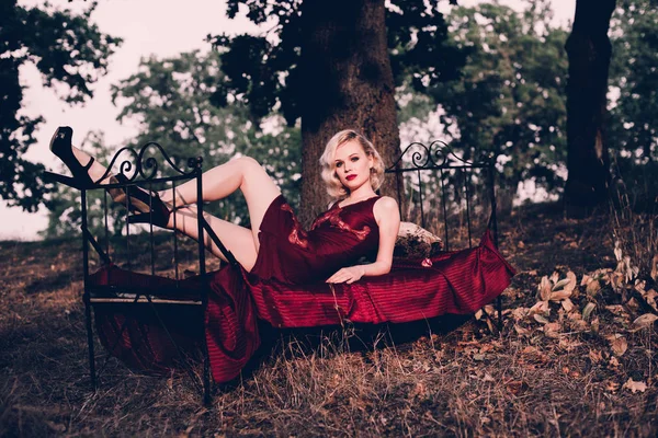 Mulher loira bonita e elegante com lábios vermelhos e ondas de cabelo vestindo vinho camisa vermelha posando na cama ao ar livre outono, estilo vintage retro e moda . — Fotografia de Stock