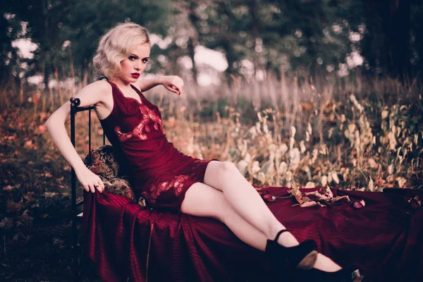 Mulher loira bonita e elegante com lábios vermelhos e ondas de cabelo vestindo vinho camisa vermelha posando na cama ao ar livre outono, estilo vintage retro e moda . — Fotografia de Stock