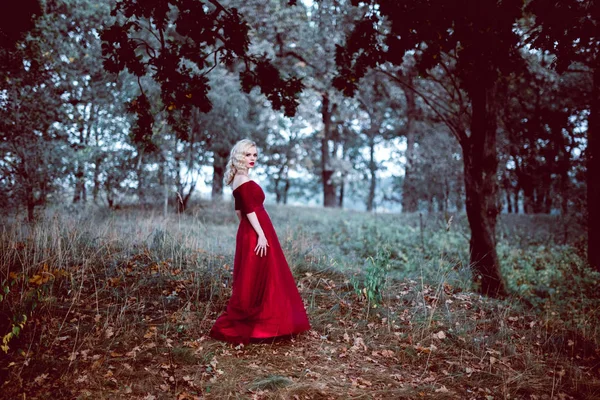 Moda linda jovem loira em belo vestido vermelho em uma floresta de conto de fadas. atmosfera mágica. tonificação tiro — Fotografia de Stock