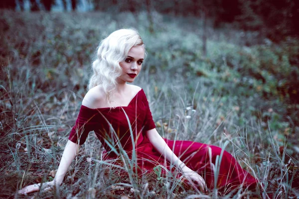 Moda linda jovem loira em belo vestido vermelho em uma floresta de conto de fadas. atmosfera mágica. tonificação tiro — Fotografia de Stock