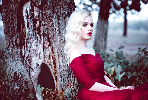Мода чудова молода блондинка в красивій червоній сукні в казковому лісі. чарівна атмосфера. тонування пострілу — стокове фото