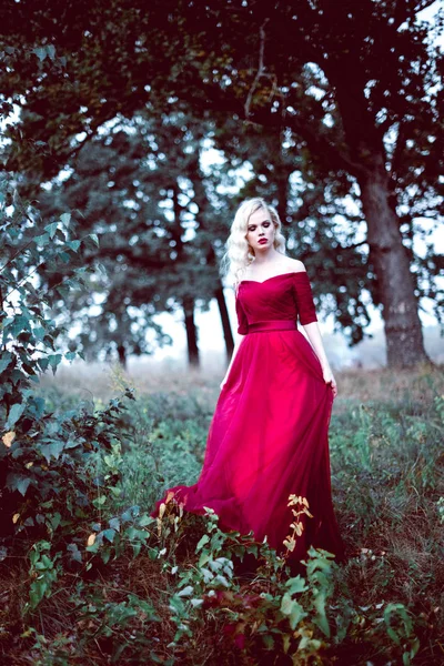 Moda linda jovem loira em belo vestido vermelho em uma floresta de conto de fadas. atmosfera mágica. tonificação tiro — Fotografia de Stock