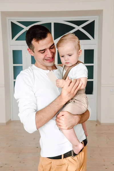 Porträt eines gut aussehenden Vaters und eines einjährigen Sohnes, die sich am Tag glücklich und lächelnd im Studio umarmen. Konzept der freundlichen Familie. — Stockfoto