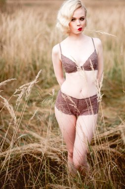 Güzel ve zarif gülümseyen seksi sarışın kadın kırmızı dudaklar ve saç giyen bej liingerie yaz, retro vintage tarzı ve moda alanında açık havada poz dalgalar. Sho tonlama düzeltisiz Güzel Sanatlar