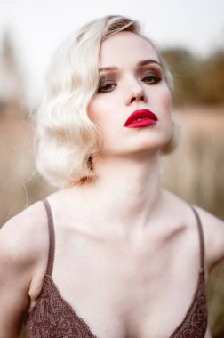 Güzel ve zarif gülümseyen seksi sarışın kadın kırmızı dudaklar ve saç giyen bej liingerie yaz, retro vintage tarzı ve moda alanında açık havada poz dalgalar. Sho tonlama düzeltisiz Güzel Sanatlar