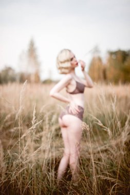 Güzel ve zarif gülümseyen seksi sarışın kadın kırmızı dudaklar ve saç giyen bej liingerie yaz, retro vintage tarzı ve moda alanında açık havada poz dalgalar. Sho tonlama düzeltisiz Güzel Sanatlar