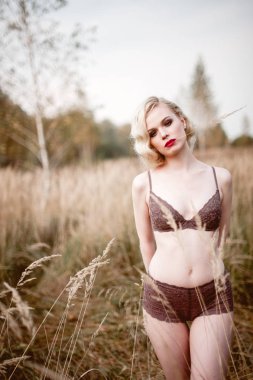 Güzel ve zarif gülümseyen seksi sarışın kadın kırmızı dudaklar ve saç giyen bej liingerie yaz, retro vintage tarzı ve moda alanında açık havada poz dalgalar. Sho tonlama düzeltisiz Güzel Sanatlar