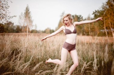 Güzel ve zarif gülümseyen seksi sarışın kadın kırmızı dudaklar ve saç giyen bej liingerie yaz, retro vintage tarzı ve moda alanında açık havada poz dalgalar. Sho tonlama düzeltisiz Güzel Sanatlar