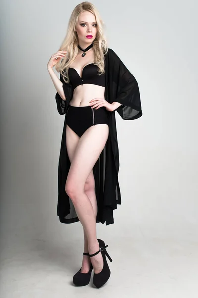 Jeune femme blonde souriante sexy en lingerie noire posant sur fond blanc . — Photo