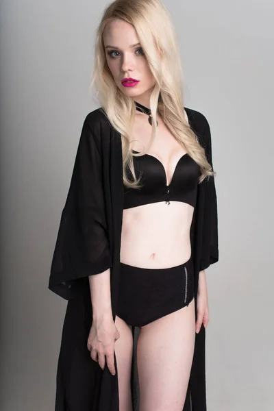 Jovem sexy sorrindo mulher loira em lingerie preta posando no fundo branco . — Fotografia de Stock
