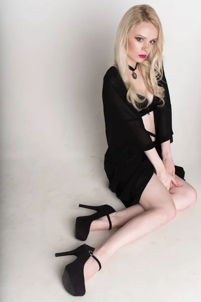 Jonge sexy lachende blonde vrouw in zwarte lingerie die zich voordeed op witte achtergrond. — Stockfoto