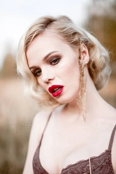Mooi en elegant lachende sexy blonde vrouw met rode lippen en haren golven dragen beige liingerie poseren op het veld buiten zomer, retro vintage stijl en mode. Geretoucheerde kunst toning sho — Stockfoto